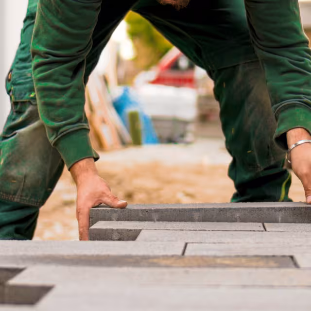 Hands laying patio blocks